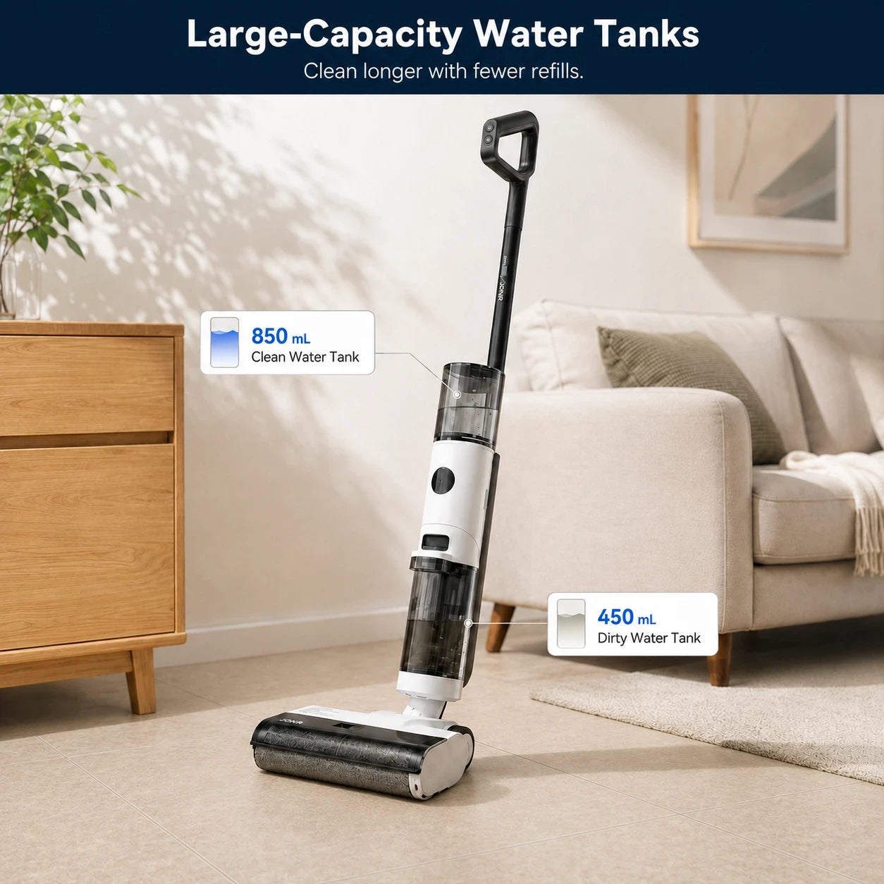 A cordless floor cleaner with a large water tank stands on a beige carpet in a living room. The product has a black, white, and transparent body, with informational callouts showing 850 mL clean water tank and 450 mL dirty water tank capacities.